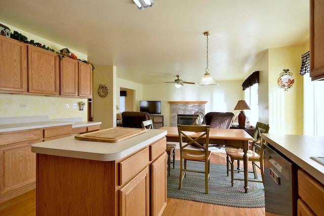 kitchen with dishwasher, a center island, hanging light fixtures, a brick fireplace, and ceiling fan