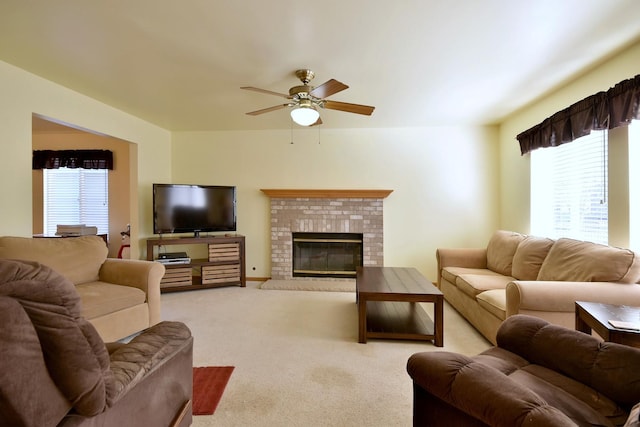 living room with a fireplace, light colored carpet, and ceiling fan