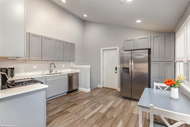 kitchen with sink, stainless steel appliances, light hardwood / wood-style flooring, high vaulted ceiling, and gray cabinets