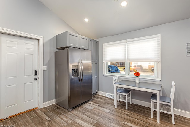 kitchen featuring stainless steel fridge, light wood-type flooring, gray cabinets, and lofted ceiling