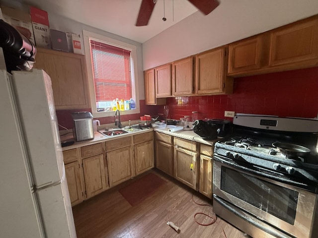 kitchen featuring sink, white fridge, ceiling fan, stainless steel gas range oven, and light wood-type flooring