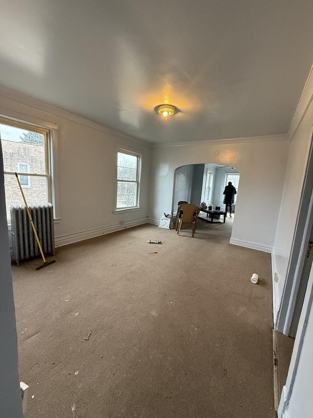 interior space with ornamental molding, radiator heating unit, and carpet flooring