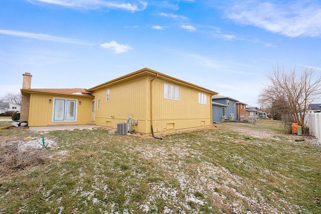 back of property with central AC unit and a yard