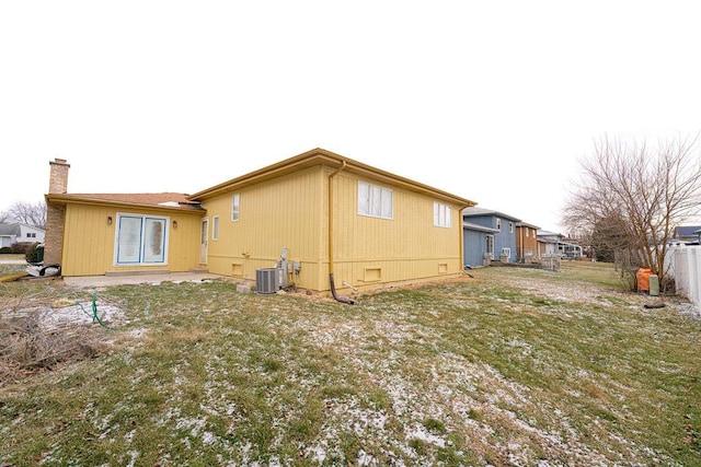 rear view of property featuring a lawn and central AC