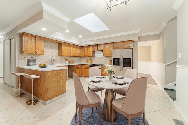 kitchen with a skylight, sink, stainless steel fridge with ice dispenser, light tile patterned floors, and ornamental molding