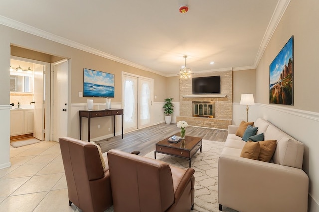 living room featuring sink, a brick fireplace, ornamental molding, light tile patterned flooring, and a chandelier