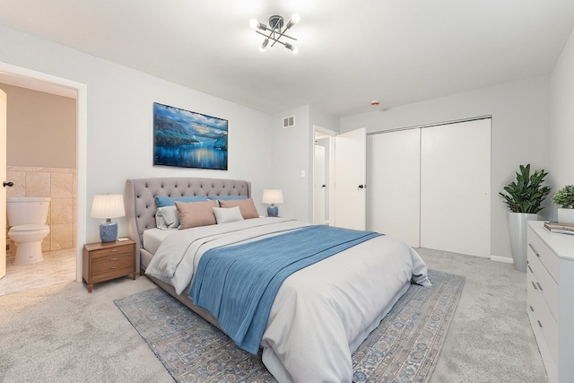 bedroom featuring ensuite bath, light carpet, and a closet