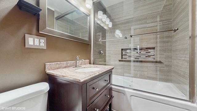 full bathroom featuring toilet, combined bath / shower with glass door, and vanity