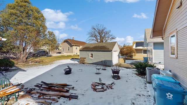 snow covered property with an outdoor fire pit, a storage unit, and central AC