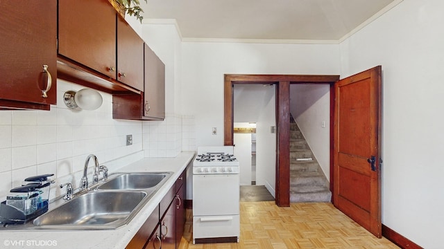 kitchen with tasteful backsplash, sink, white gas range, ornamental molding, and light parquet floors