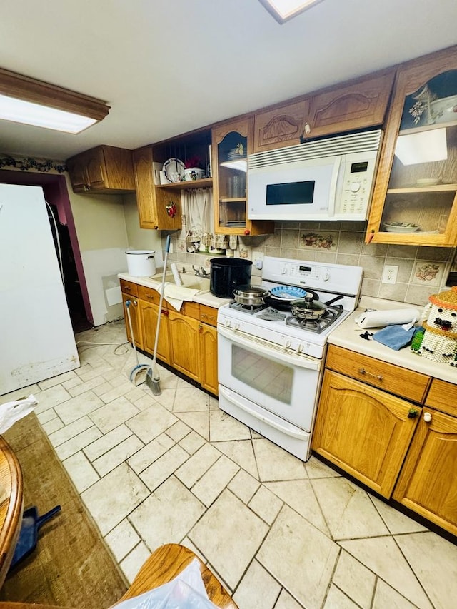 kitchen with backsplash, sink, and white appliances