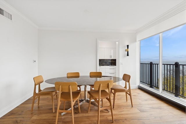 dining space with baseboards, ornamental molding, light wood-type flooring, and visible vents
