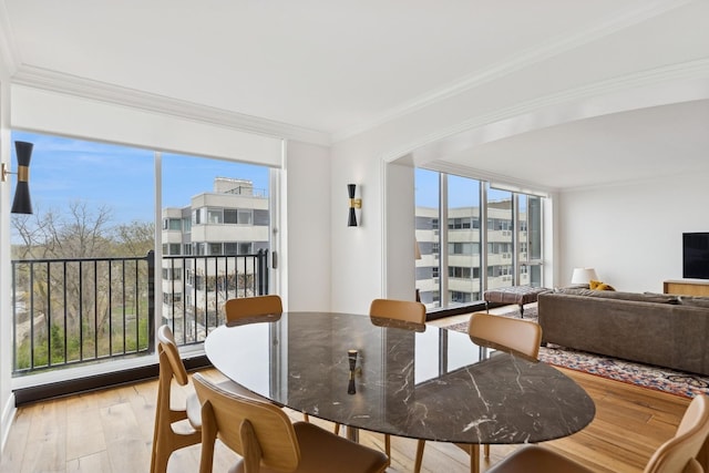 dining area featuring ornamental molding, light wood-style flooring, and a wealth of natural light