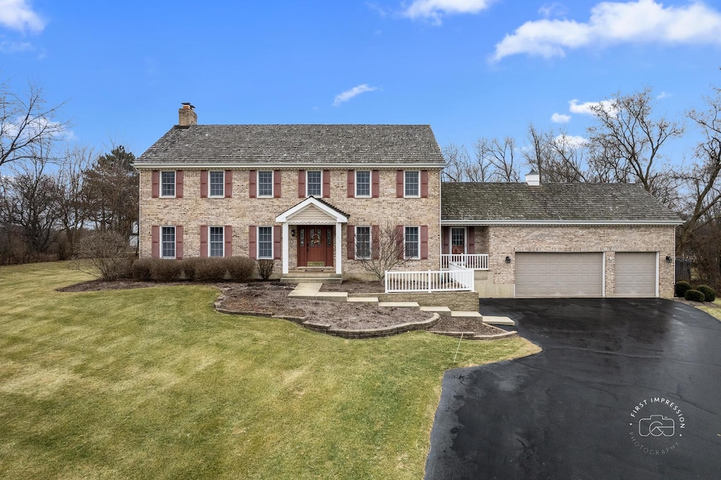 colonial inspired home featuring a garage and a front lawn