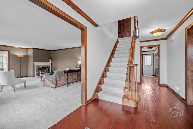 stairway featuring hardwood / wood-style flooring, a brick fireplace, and crown molding