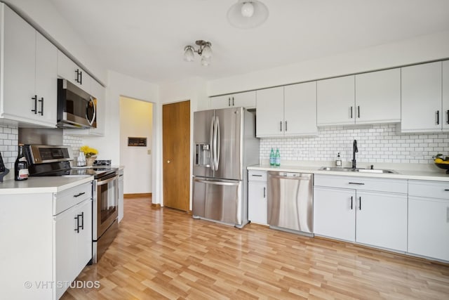 kitchen with decorative backsplash, sink, white cabinetry, and stainless steel appliances