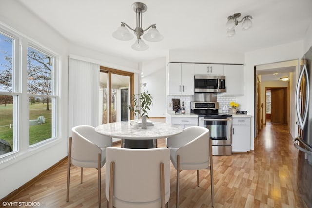 kitchen with stainless steel appliances, tasteful backsplash, plenty of natural light, white cabinets, and light wood-type flooring