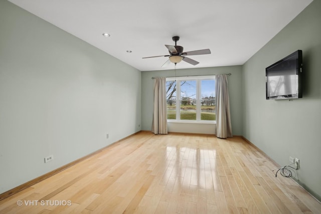 empty room with ceiling fan and light hardwood / wood-style flooring