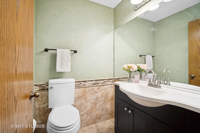 bathroom with vanity, toilet, and tile walls