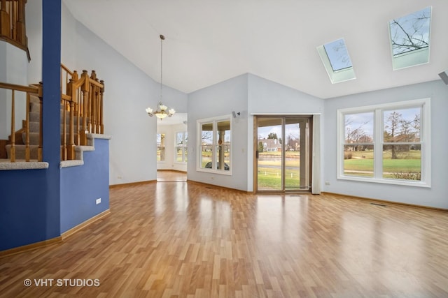 unfurnished living room with hardwood / wood-style flooring, a notable chandelier, high vaulted ceiling, and a skylight