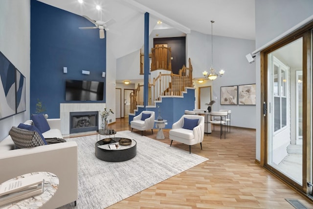 living room with a fireplace, hardwood / wood-style floors, ceiling fan with notable chandelier, and high vaulted ceiling