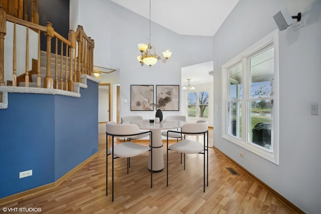 dining room featuring hardwood / wood-style floors, high vaulted ceiling, and an inviting chandelier