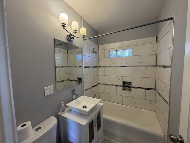 full bathroom featuring vanity, tiled shower / bath combo, and toilet