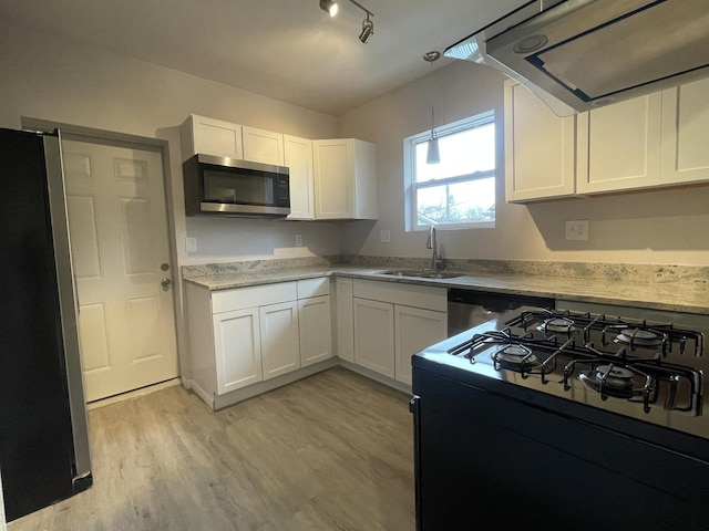 kitchen with light wood-type flooring, stainless steel appliances, sink, pendant lighting, and white cabinetry