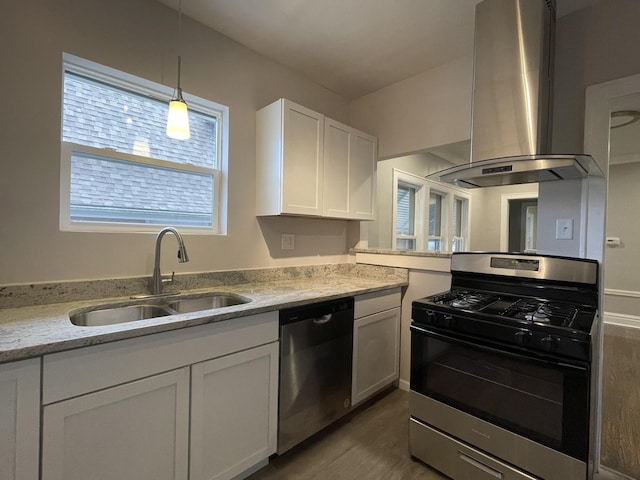 kitchen with appliances with stainless steel finishes, light stone counters, island range hood, sink, and white cabinets