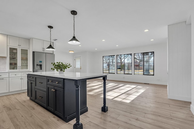 kitchen featuring white cabinetry, a kitchen island, hanging light fixtures, and stainless steel refrigerator with ice dispenser