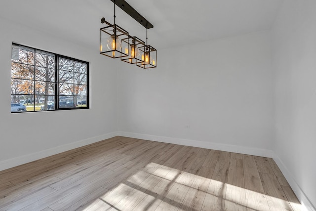 unfurnished dining area featuring light hardwood / wood-style floors, beam ceiling, and an inviting chandelier