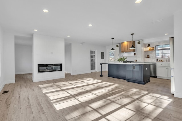 kitchen featuring white cabinetry, dishwasher, pendant lighting, a fireplace, and a kitchen island