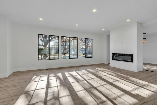 unfurnished living room featuring a fireplace, light hardwood / wood-style flooring, and heating unit