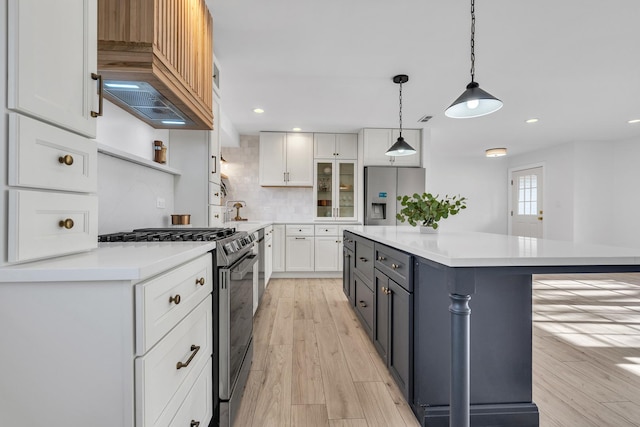 kitchen with a center island, white cabinetry, stainless steel appliances, and hanging light fixtures