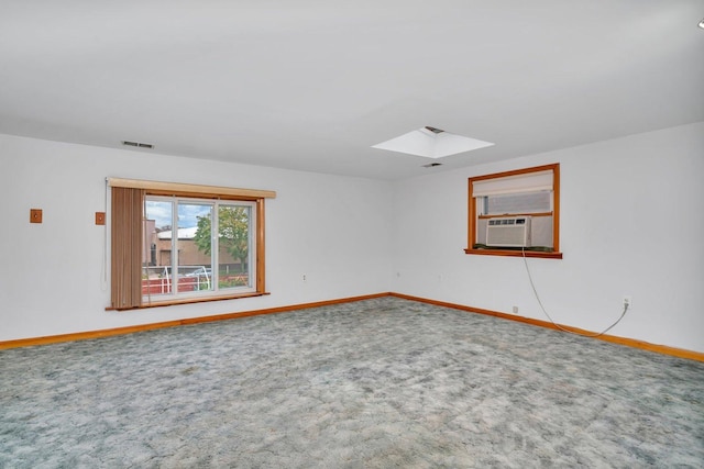 empty room with cooling unit, a skylight, and carpet floors