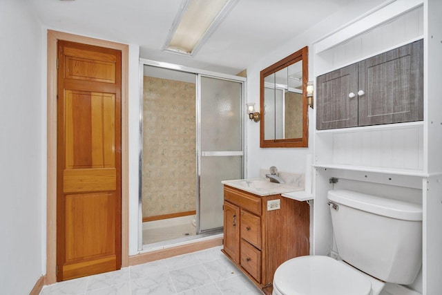 bathroom featuring a shower with door, vanity, and toilet