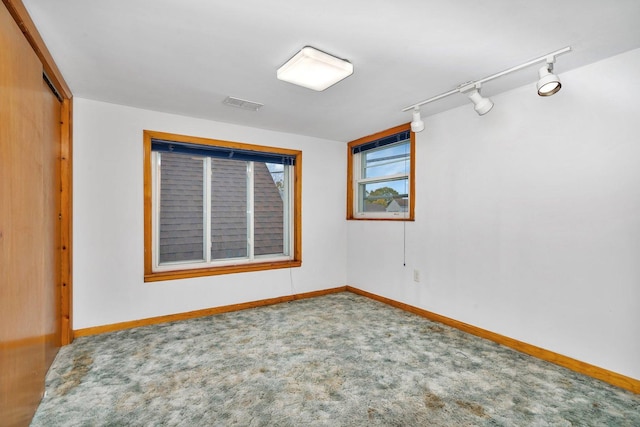 carpeted spare room featuring rail lighting