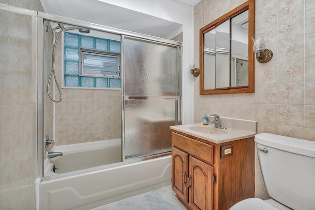 full bathroom featuring vanity, toilet, shower / bath combination with glass door, and tile walls