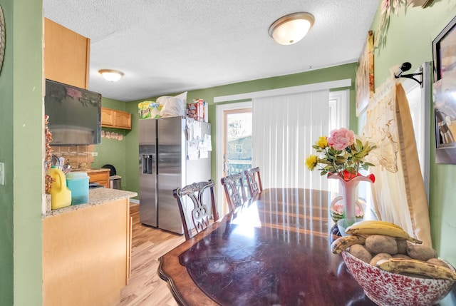 dining area featuring a textured ceiling and light hardwood / wood-style flooring