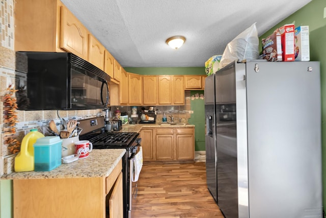 kitchen featuring light brown cabinets, stainless steel appliances, a textured ceiling, and light hardwood / wood-style flooring