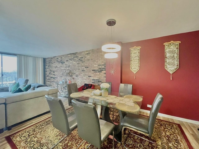 dining area featuring hardwood / wood-style floors and brick wall