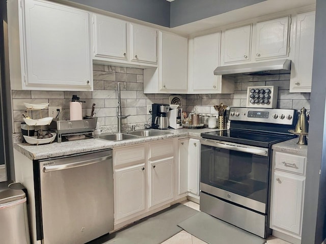 kitchen with sink, white cabinetry, light tile patterned floors, decorative backsplash, and appliances with stainless steel finishes