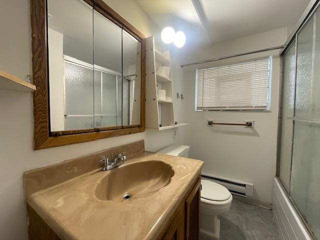 full bathroom with vanity, a baseboard radiator, toilet, and bath / shower combo with glass door