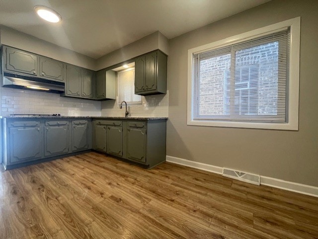 kitchen with cooktop, tasteful backsplash, hardwood / wood-style flooring, and sink