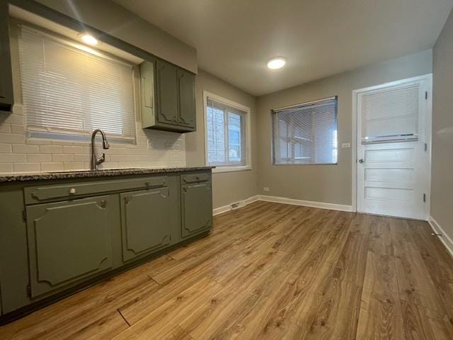 kitchen featuring tasteful backsplash, green cabinets, sink, and light wood-type flooring