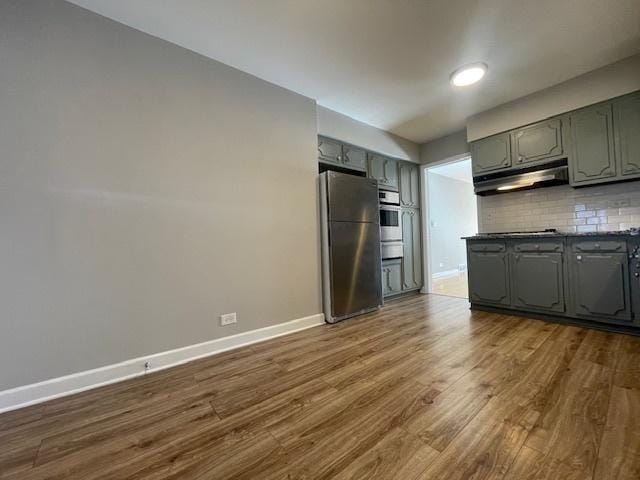 kitchen with appliances with stainless steel finishes, backsplash, and wood-type flooring