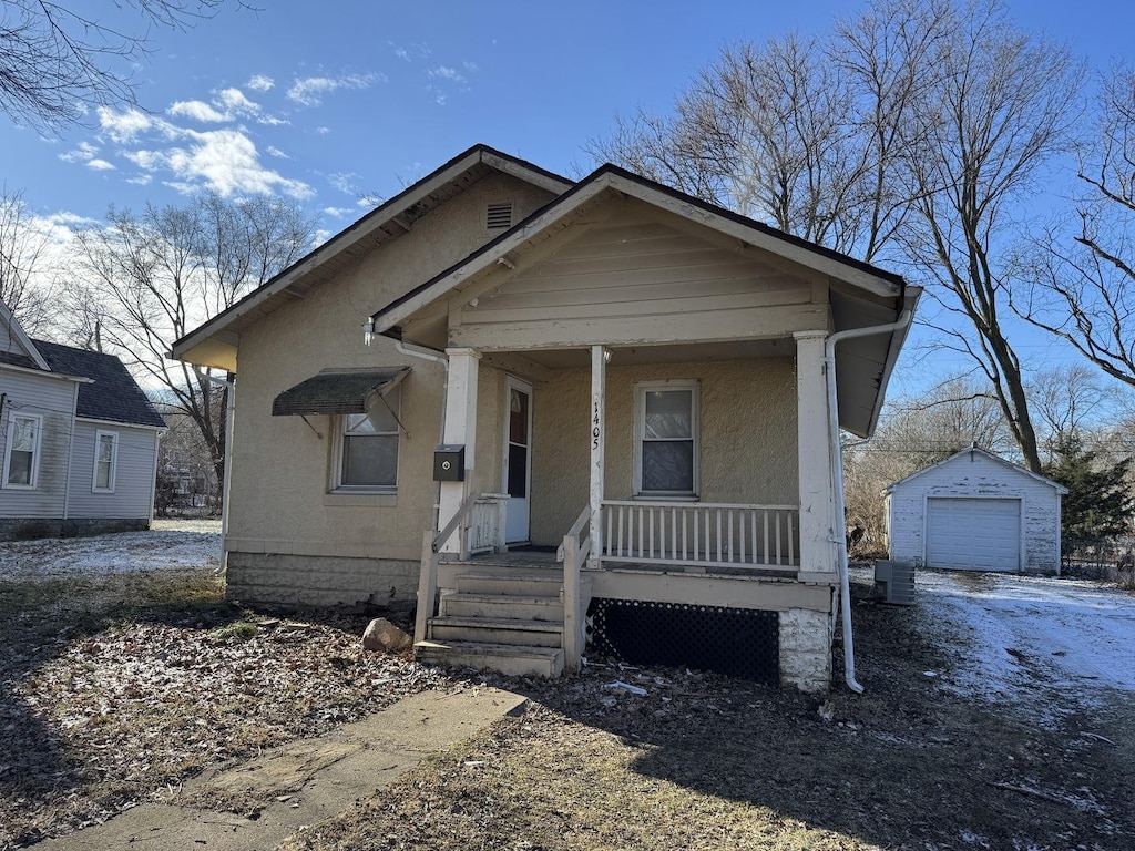 bungalow with an outbuilding, cooling unit, a porch, and a garage