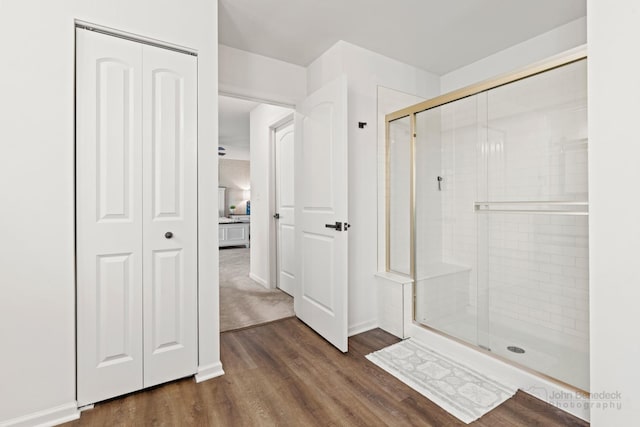 bathroom with wood finished floors, a shower stall, and baseboards