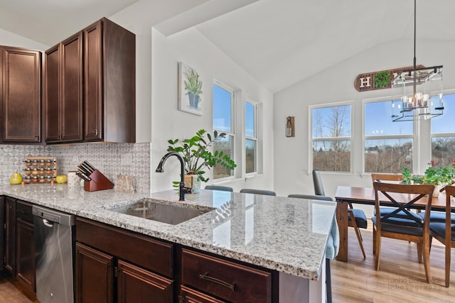 kitchen with light stone counters, light wood finished floors, decorative backsplash, a sink, and dishwasher