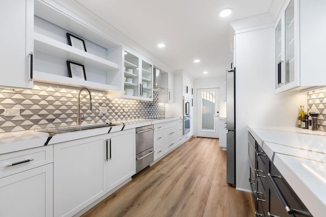 kitchen featuring light wood finished floors, white cabinetry, light countertops, and a sink